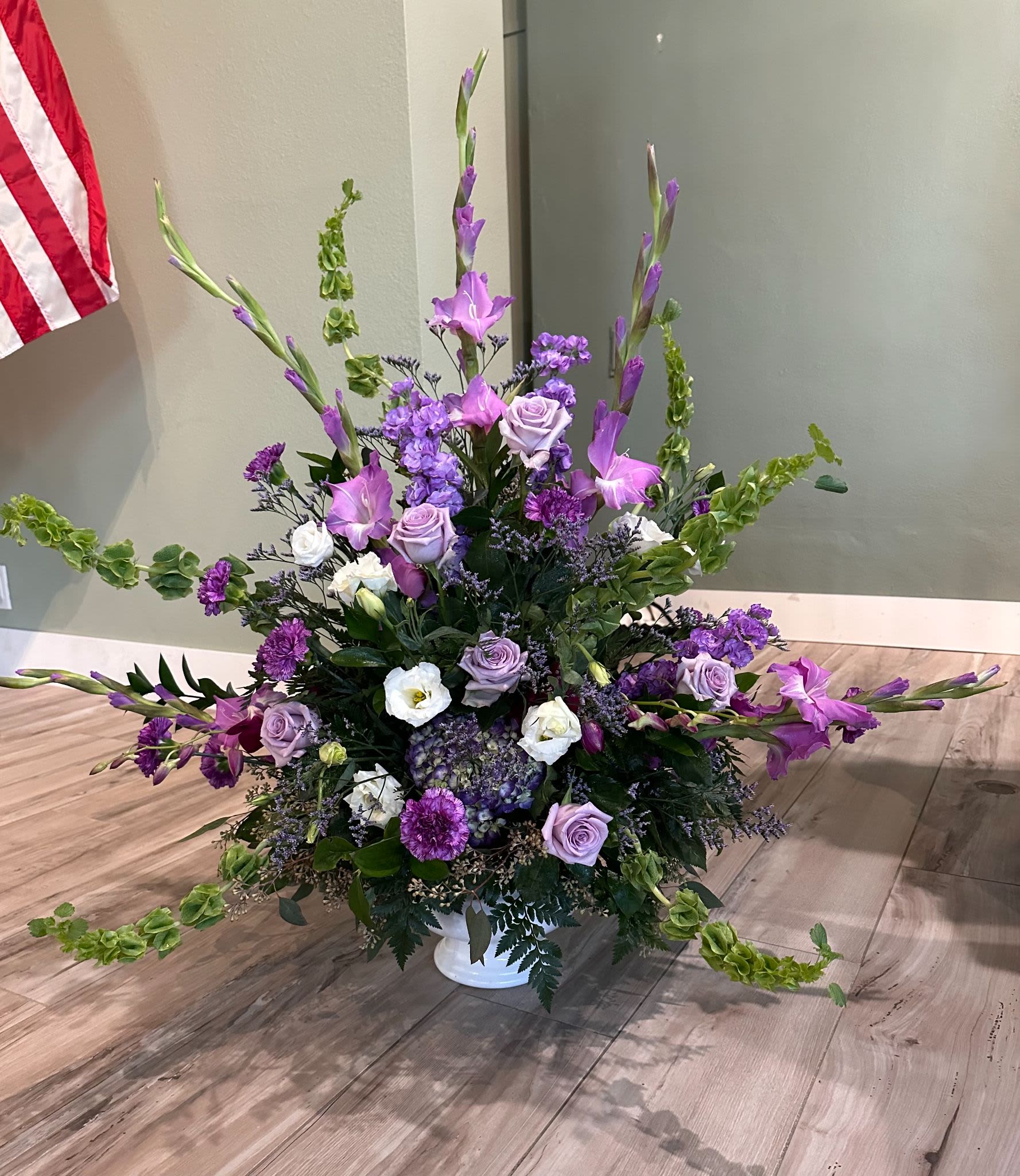 Large purple and white floral arrangement in a white vase