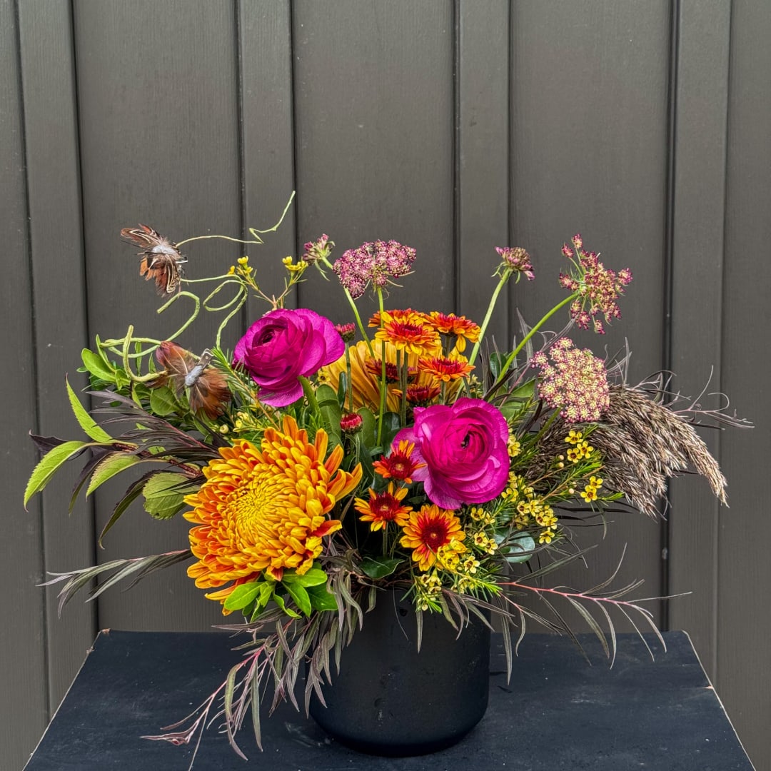 Colorful floral arrangement in a black vase with magenta and orange blooms