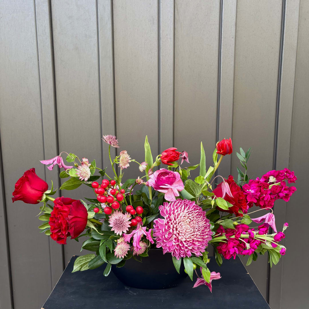 Pink and red mixed flower arrangement in a black container