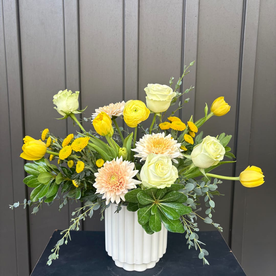 Yellow tulips and pale roses in a white vase with peach chrysanthemums