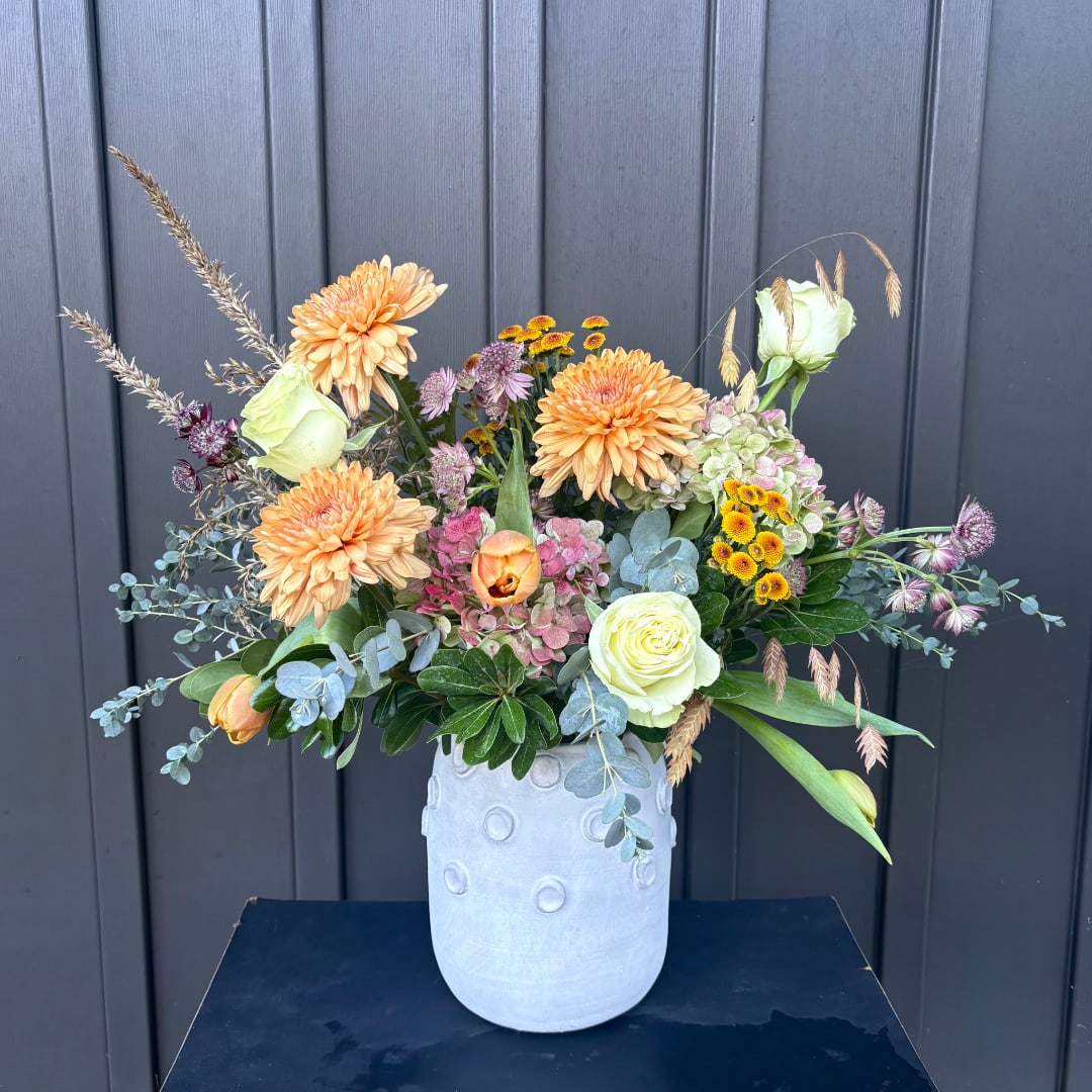 Mixed peach and white flowers arranged in a pale vase