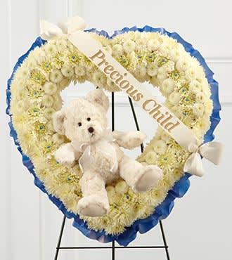 Heart-shaped white floral wreath with a teddy bear and ribbon banner