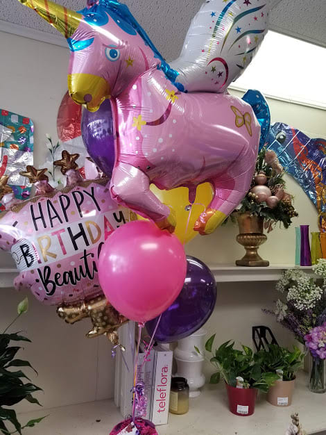 Unicorn-shaped birthday balloons with a pink birthday balloon and a pink helium balloon
