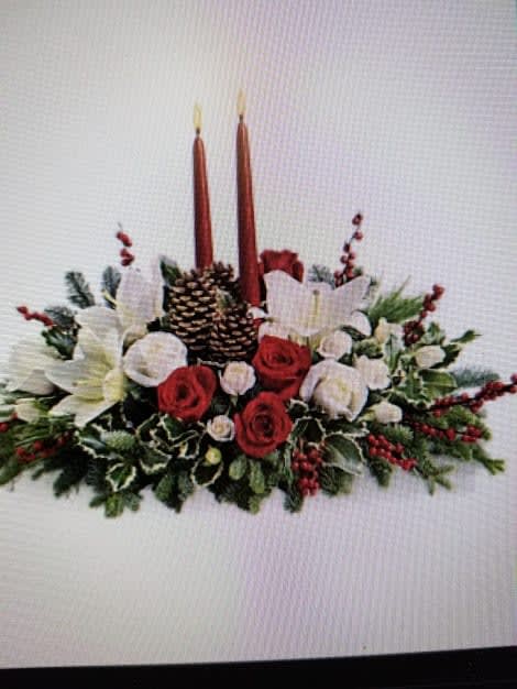 Holiday centerpiece with red and white flowers, pinecones, and two tall candles