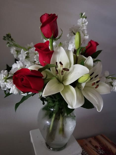 Red roses and white lilies arranged in a glass vase