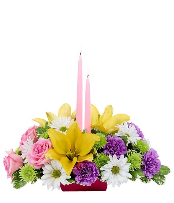Pink candles in a mixed flower centerpiece with yellow lilies and daisies