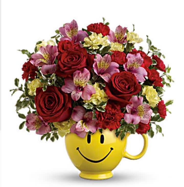 Bouquet of red roses, pink alstroemeria, and carnations in a yellow smiley-face mug