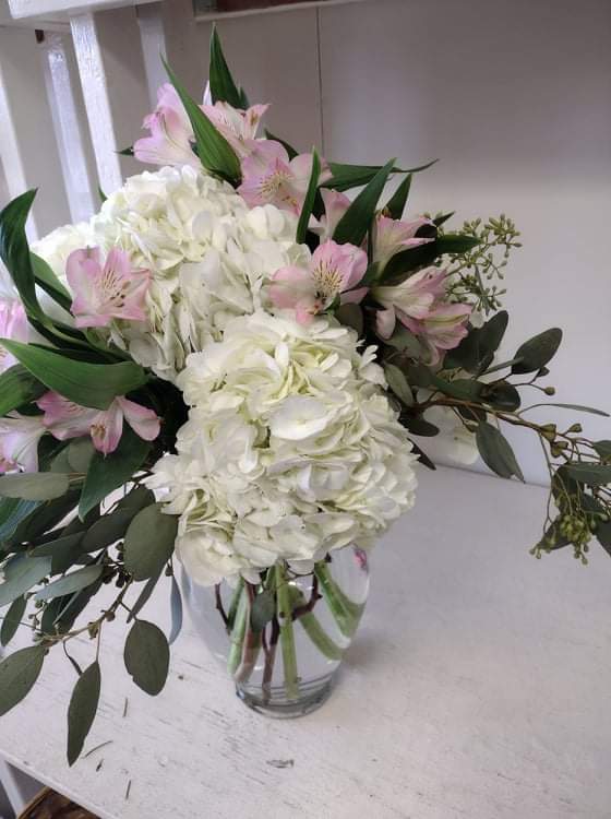 White hydrangeas and pink lilies in a clear glass vase