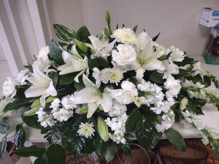 White lilies and chrysanthemums arranged in a low casket spray
