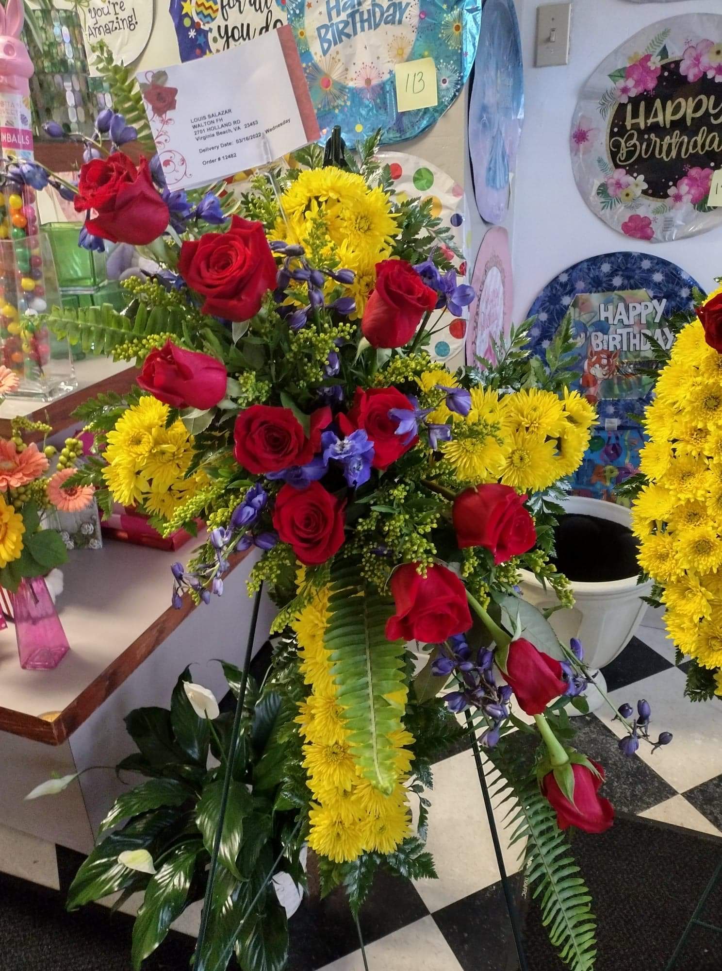Tall floral spray with red roses, yellow chrysanthemums, and purple accents