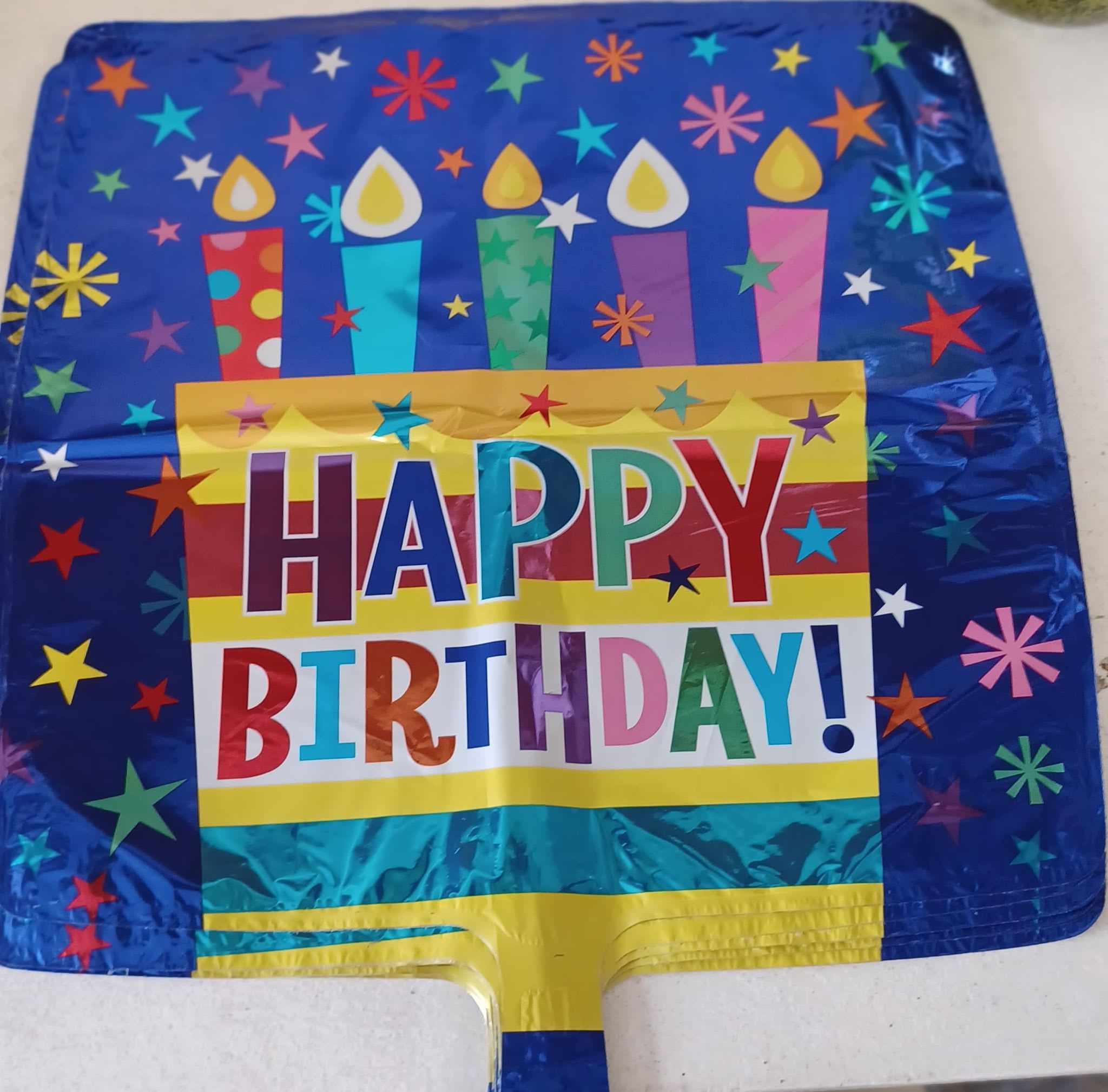Square foil birthday balloon with colorful candles and Happy Birthday text on blue background