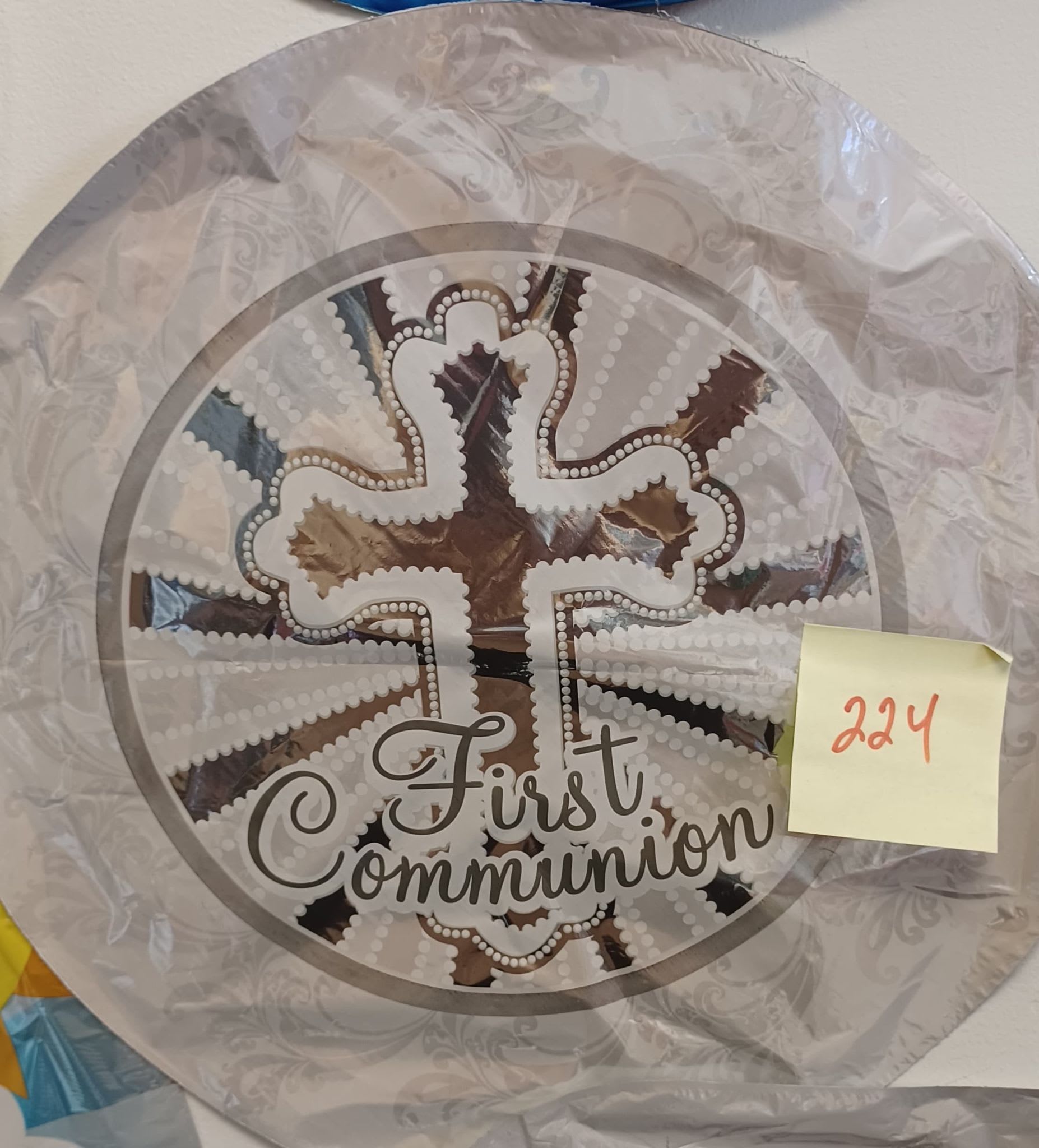 Round decorative plaque with a cross and the words First Communion