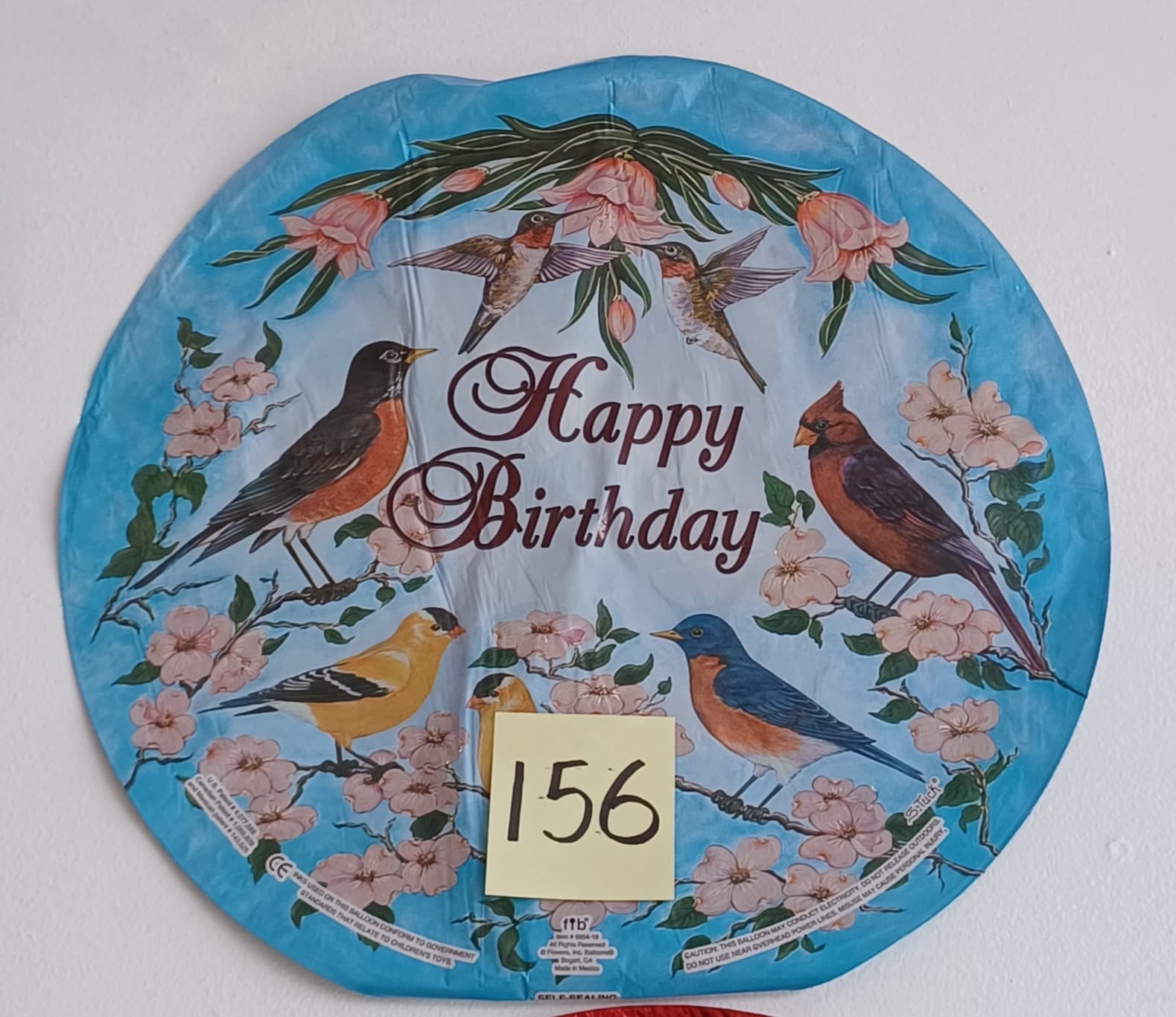 Round blue birthday balloon with birds and pink blossoms