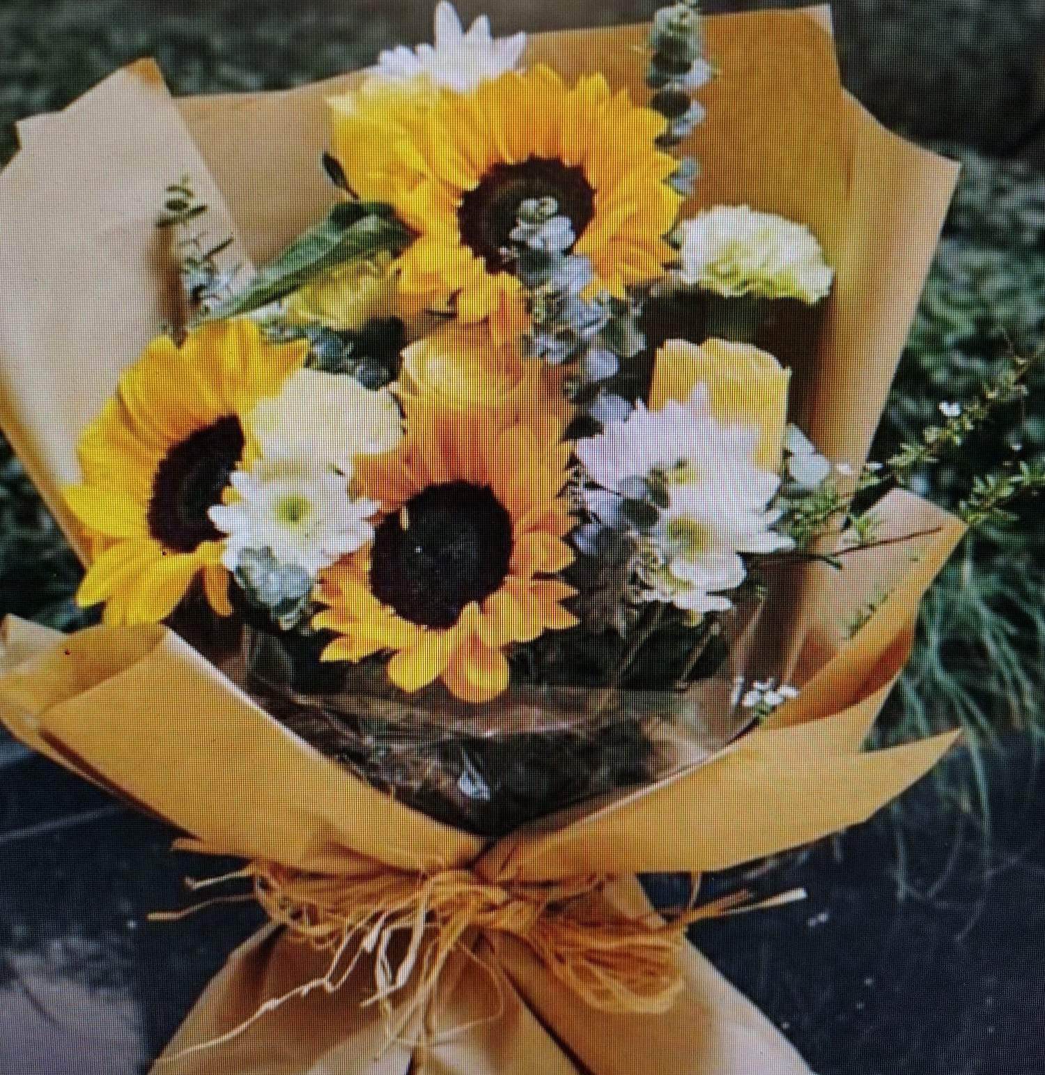 Bouquet of sunflowers and white daisies wrapped in brown paper