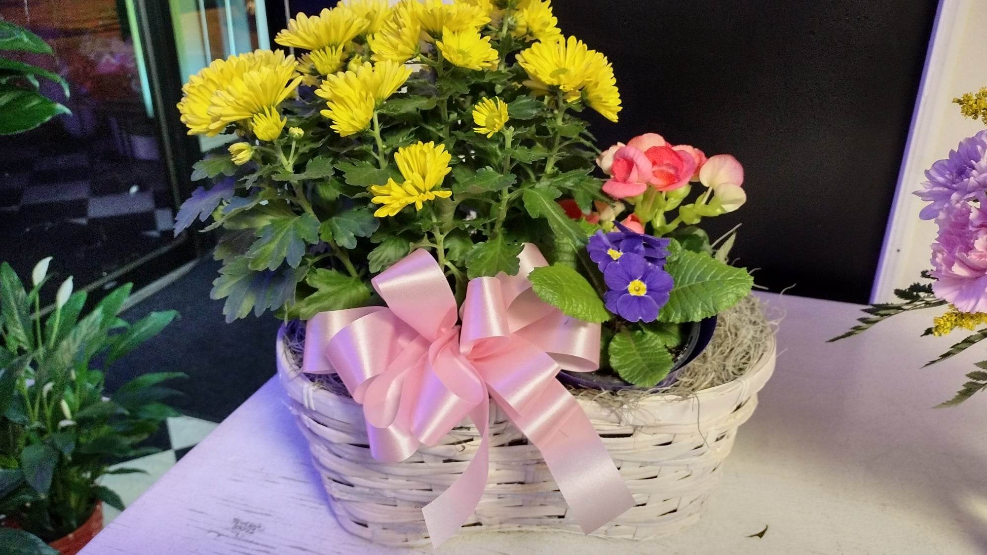 Basket of yellow and pink flowers with a pink ribbon