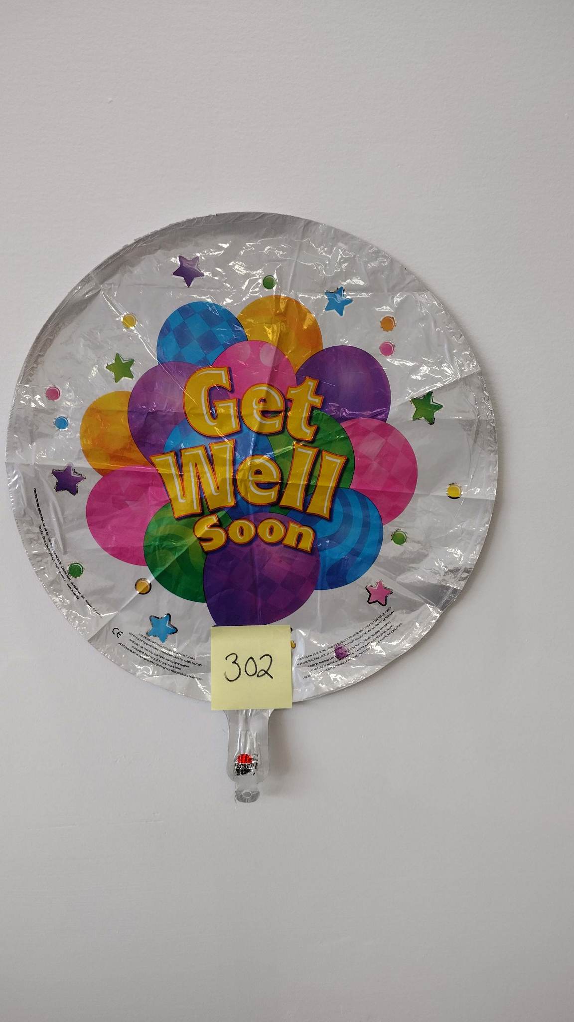 Round foil balloon reading "Get Well Soon" in bright colors