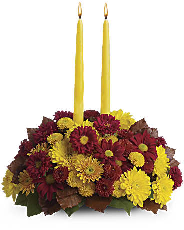 Yellow taper candles in a low arrangement of red and yellow mums