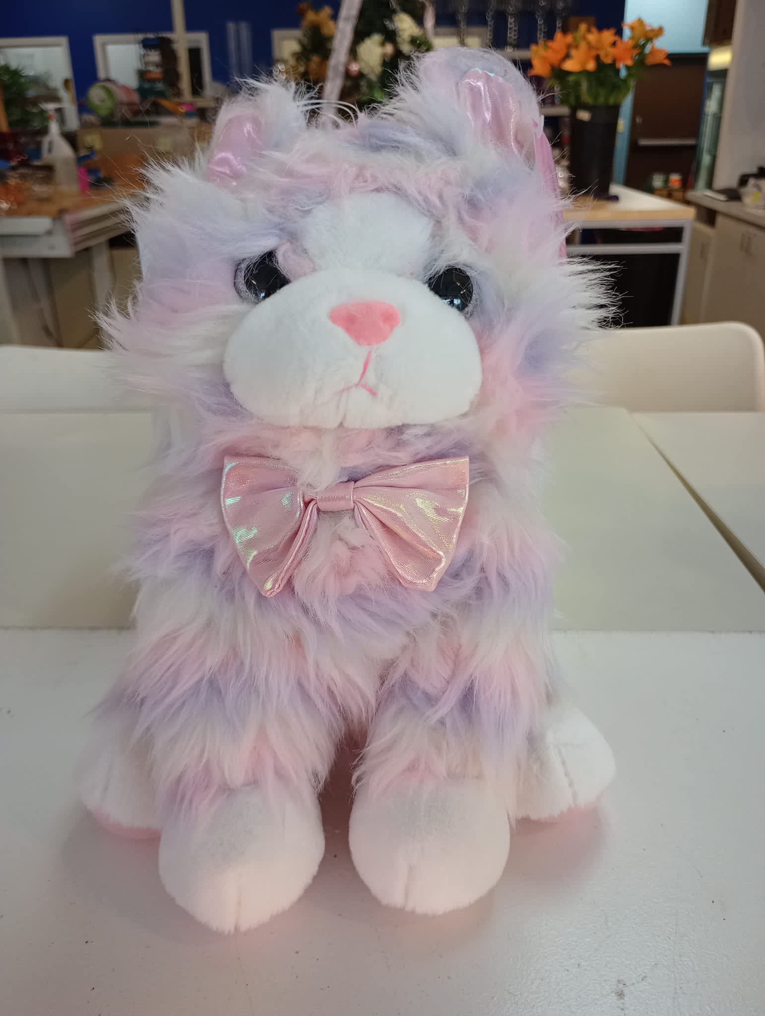 Pastel plush cat with a pink bow sitting on a table