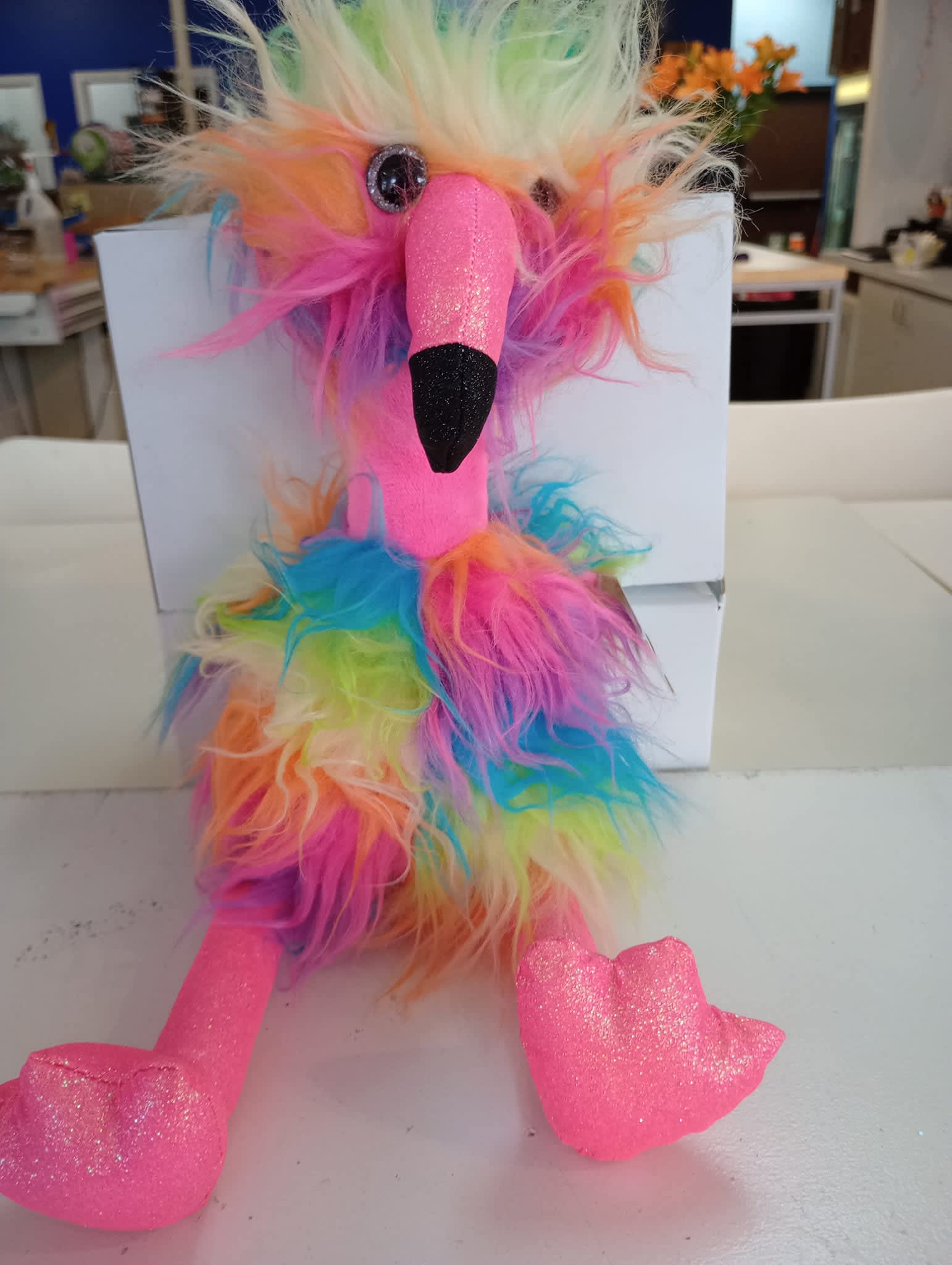 Rainbow plush bird toy with fuzzy multicolor fur and glittery pink beak and feet