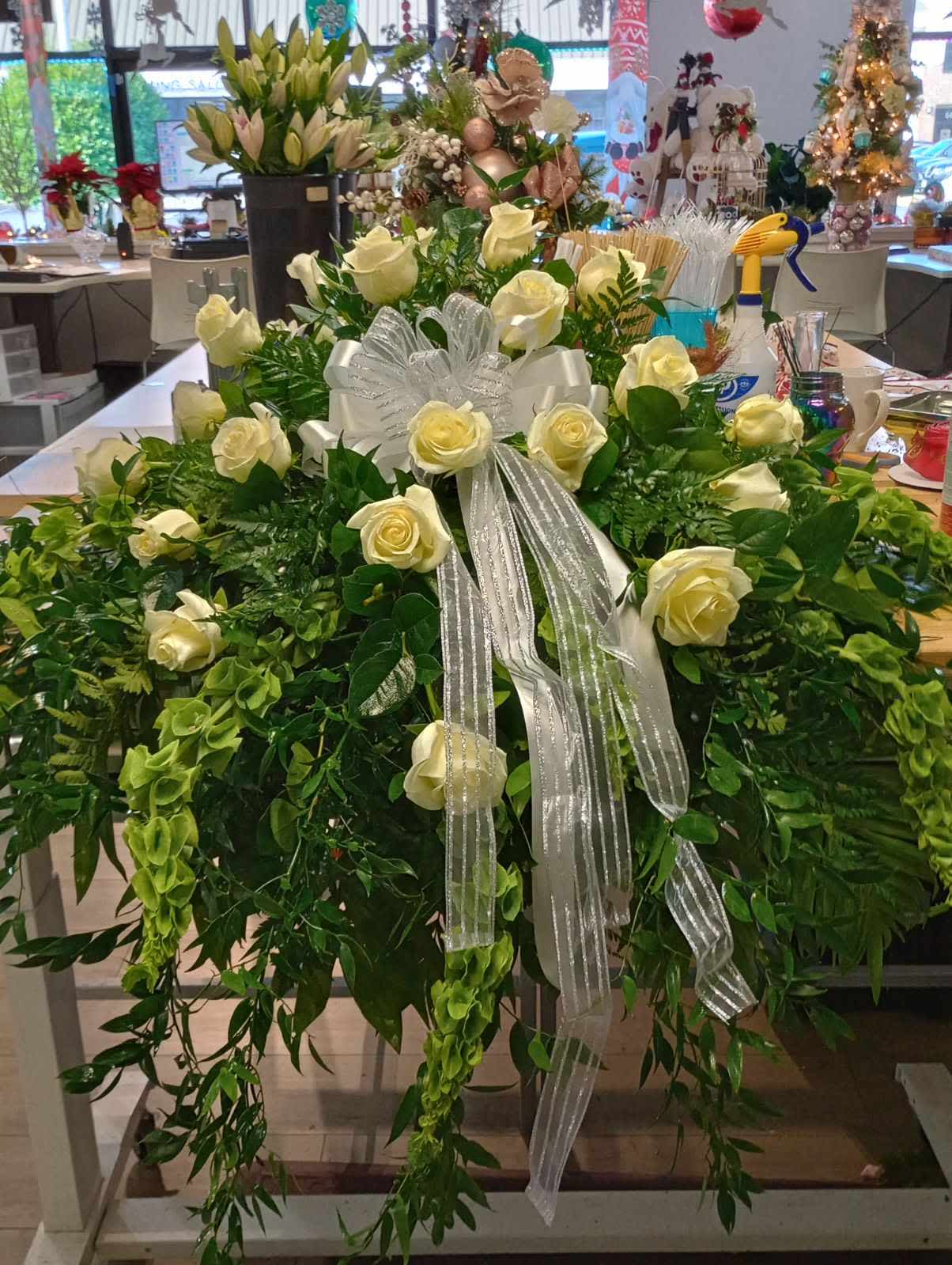 Large white rose arrangement with a silver ribbon and cascading greenery