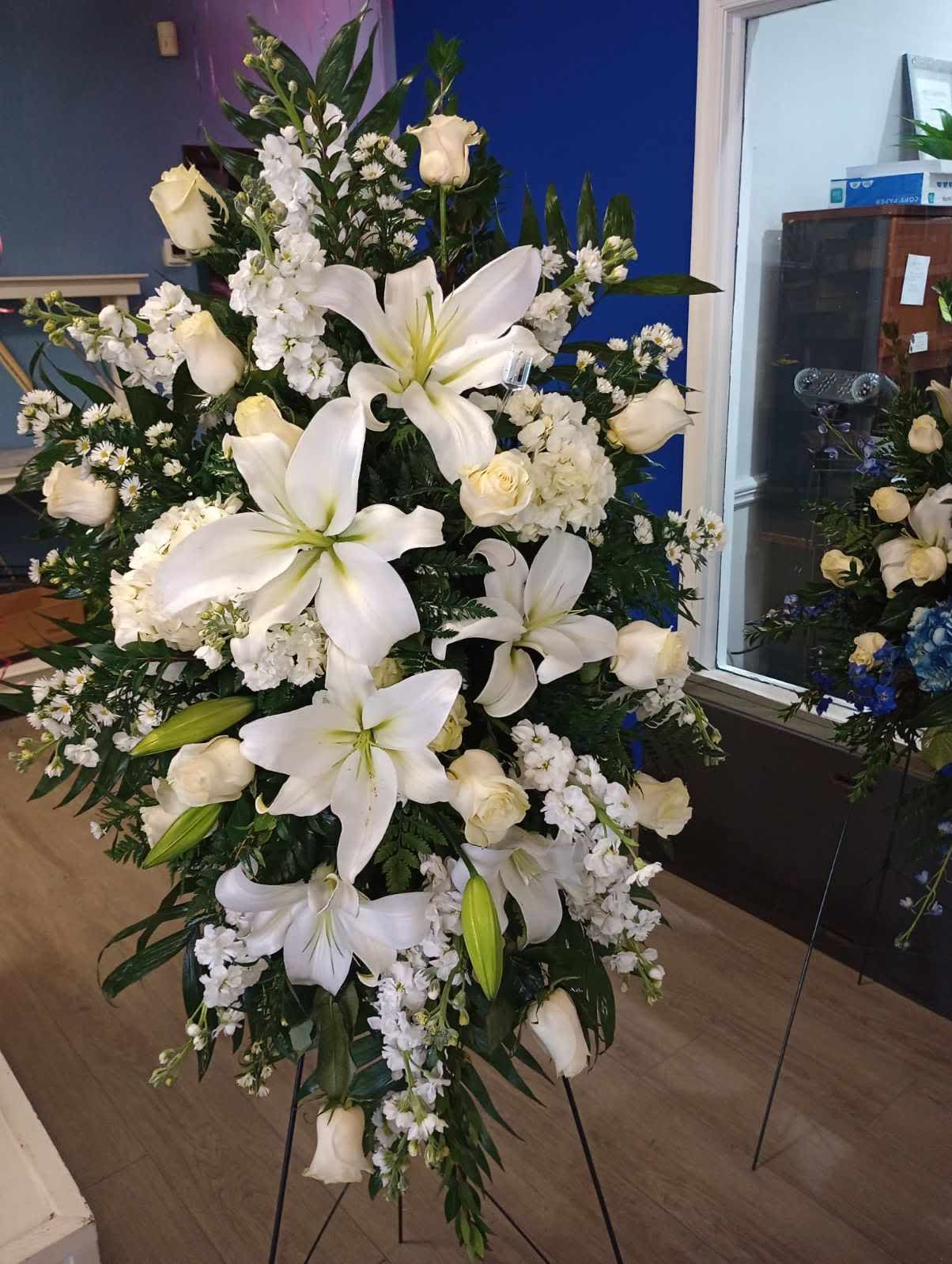 Large white funeral spray with lilies and roses on a stand