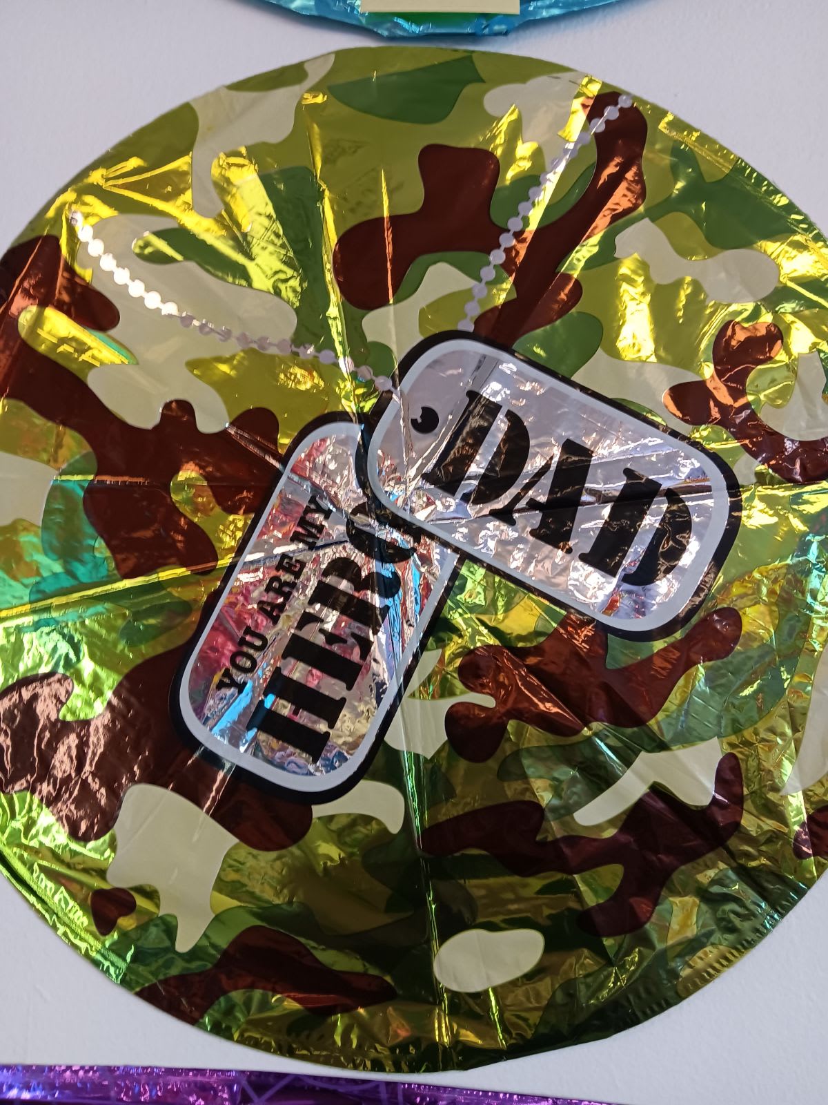 Camouflage-patterned round foil balloon with a "Dad" label
