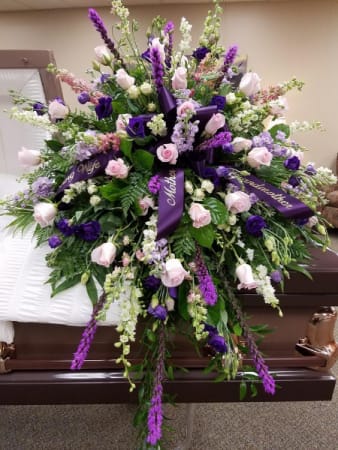 Large purple and pink funeral spray on a casket