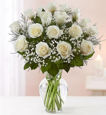 White roses arranged in a clear glass vase with baby's breath