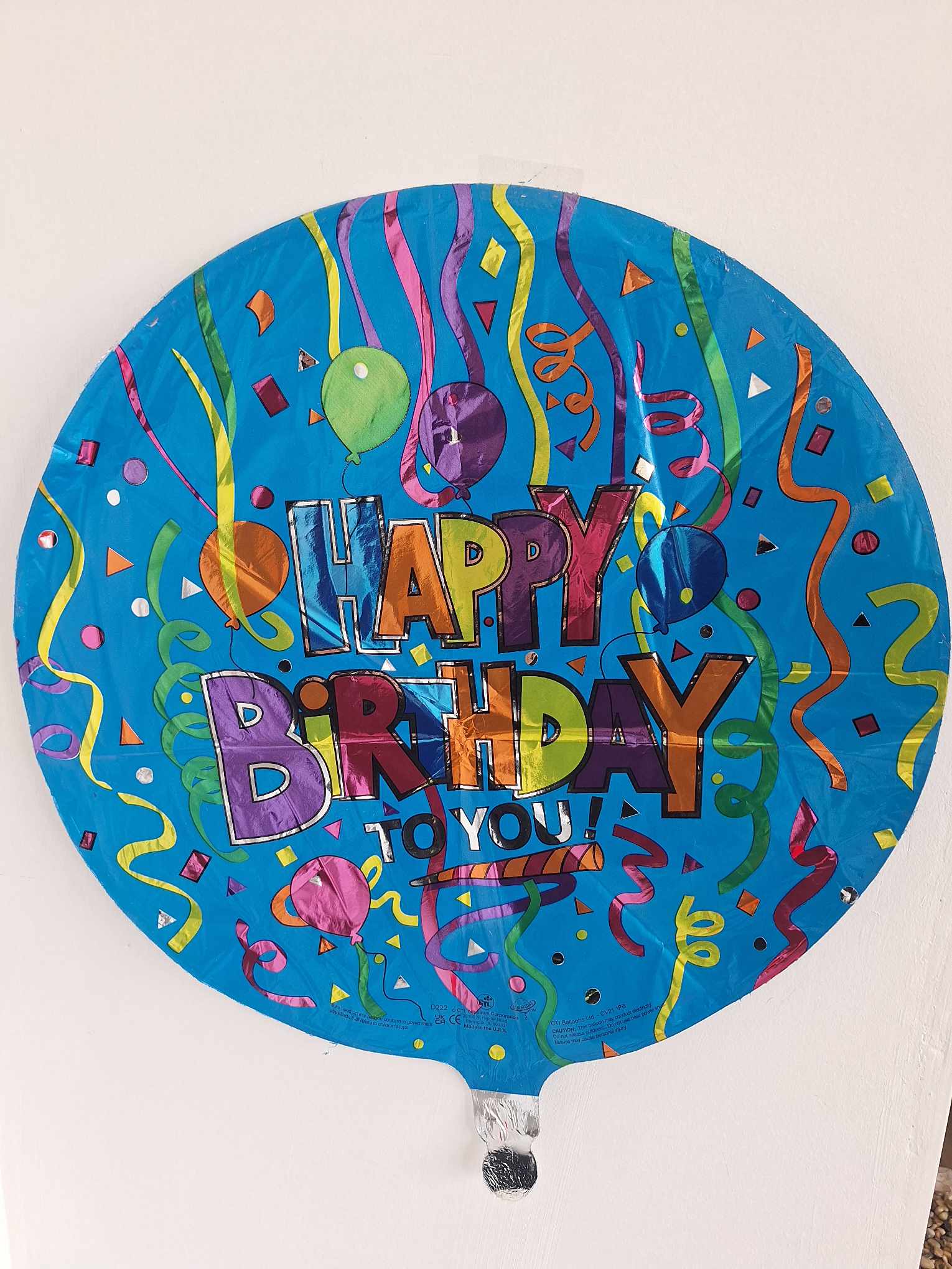 Round blue birthday balloon with colorful confetti and "Happy Birthday" text