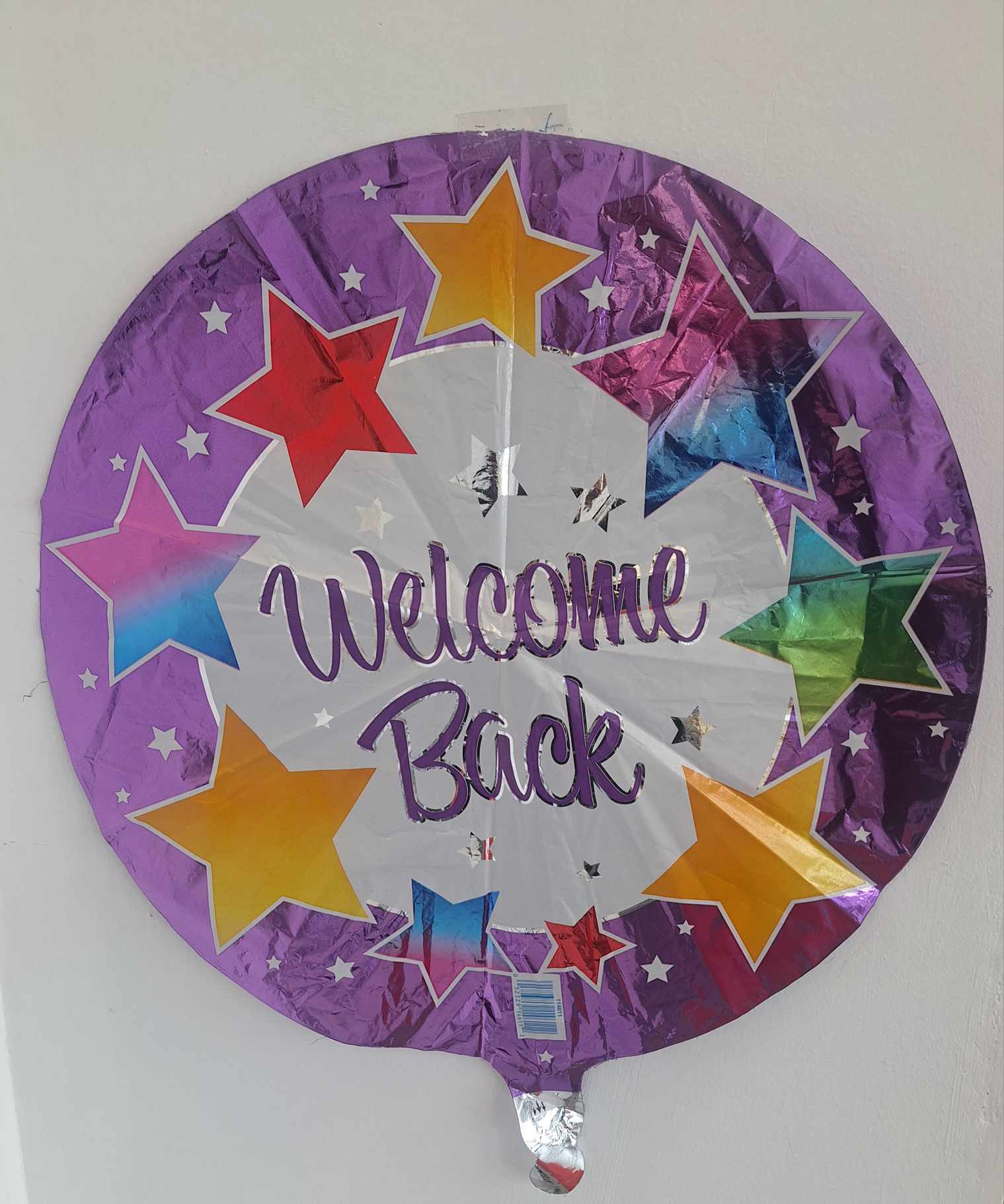 Round purple foil balloon with stars and the words Welcome Back