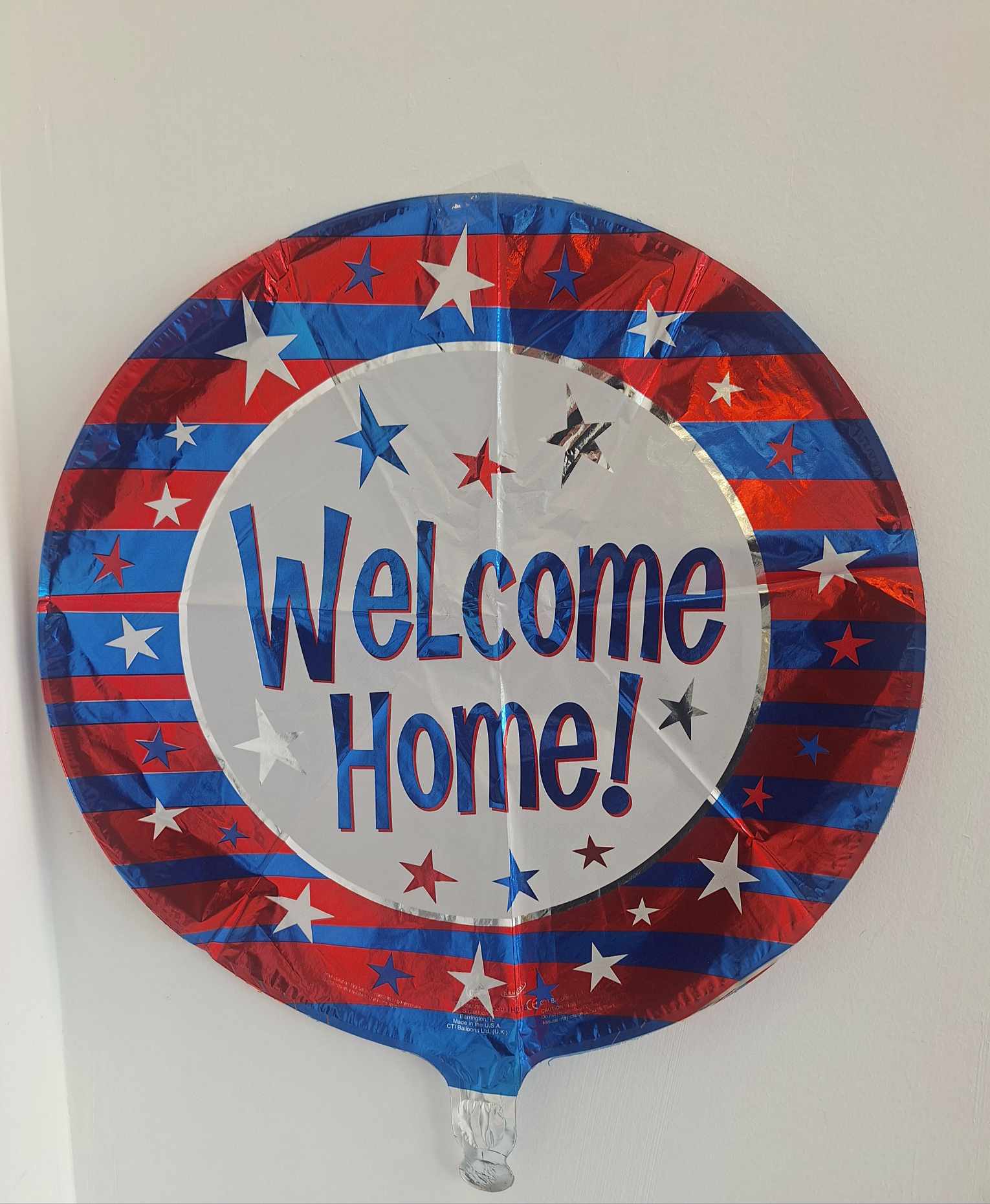 Round foil balloon with "Welcome Home!" text in red, white, and blue