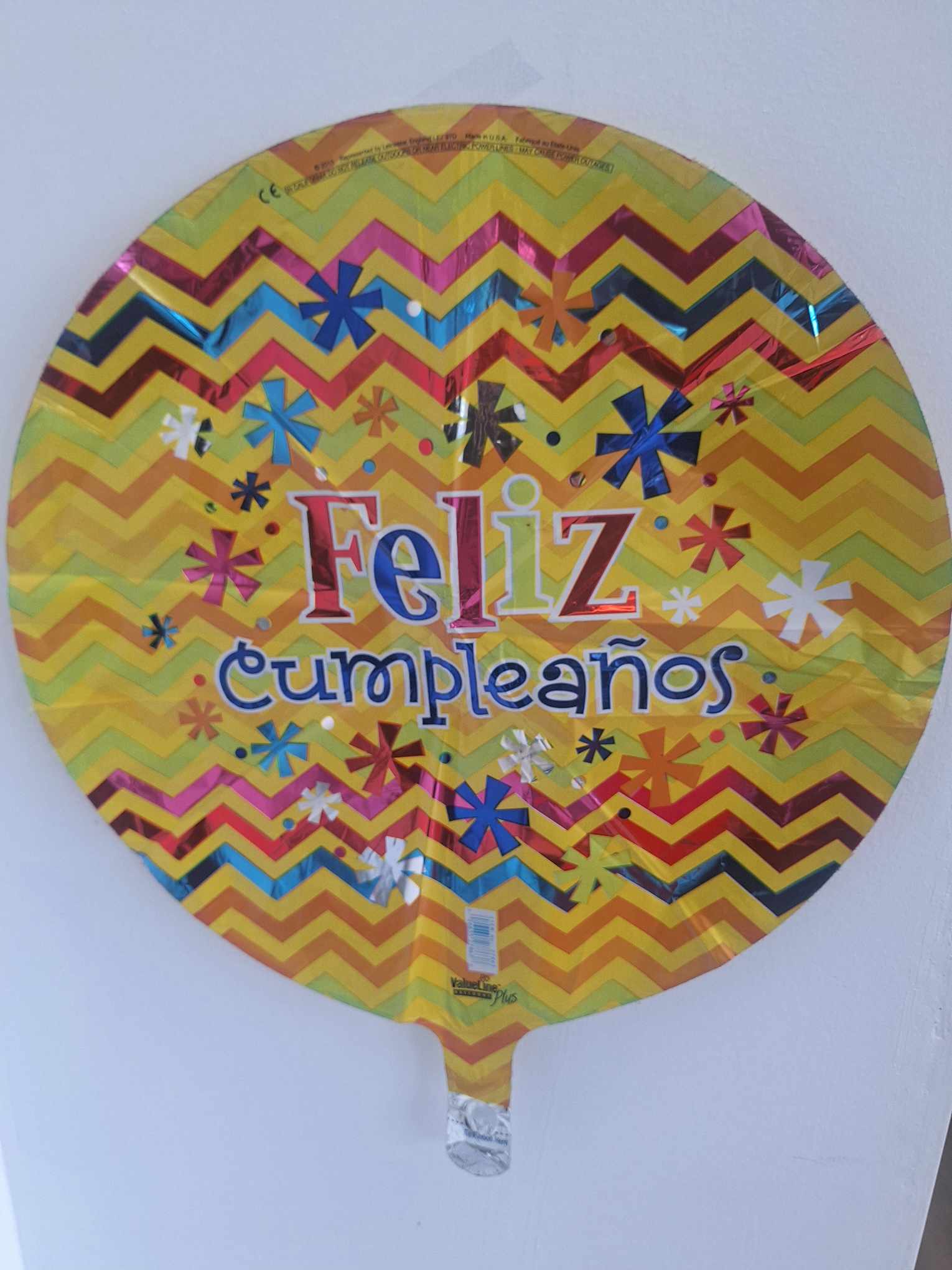 Round foil balloon with "Feliz cumpleaños" text and colorful zigzag pattern