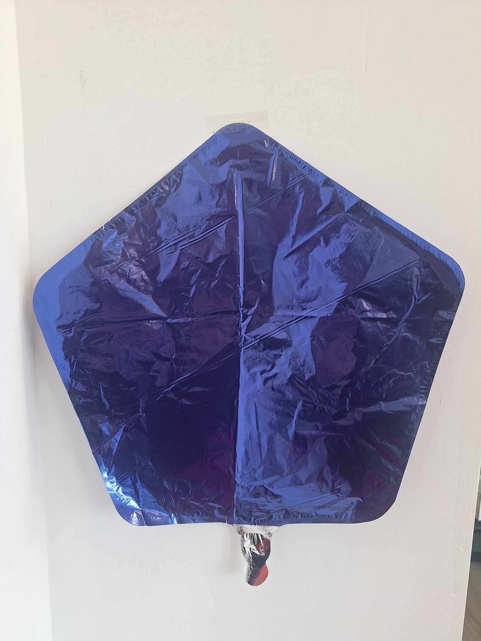 Blue star-shaped foil balloon against a white wall