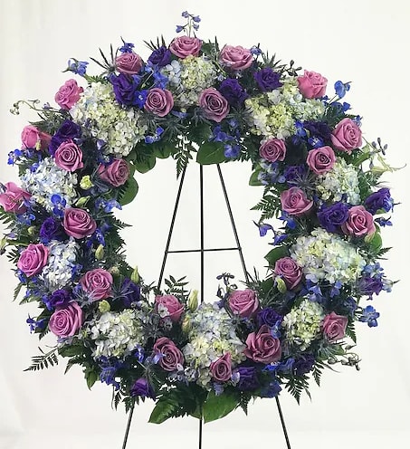Purple and blue floral wreath on a black stand