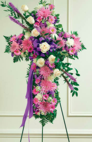 Standing floral cross with pink and white flowers and a purple ribbon