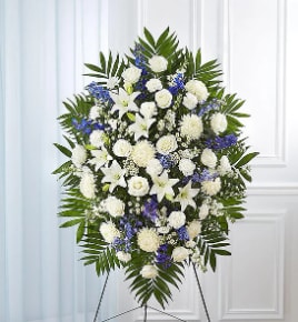 Standing funeral spray of white and blue flowers on an easel