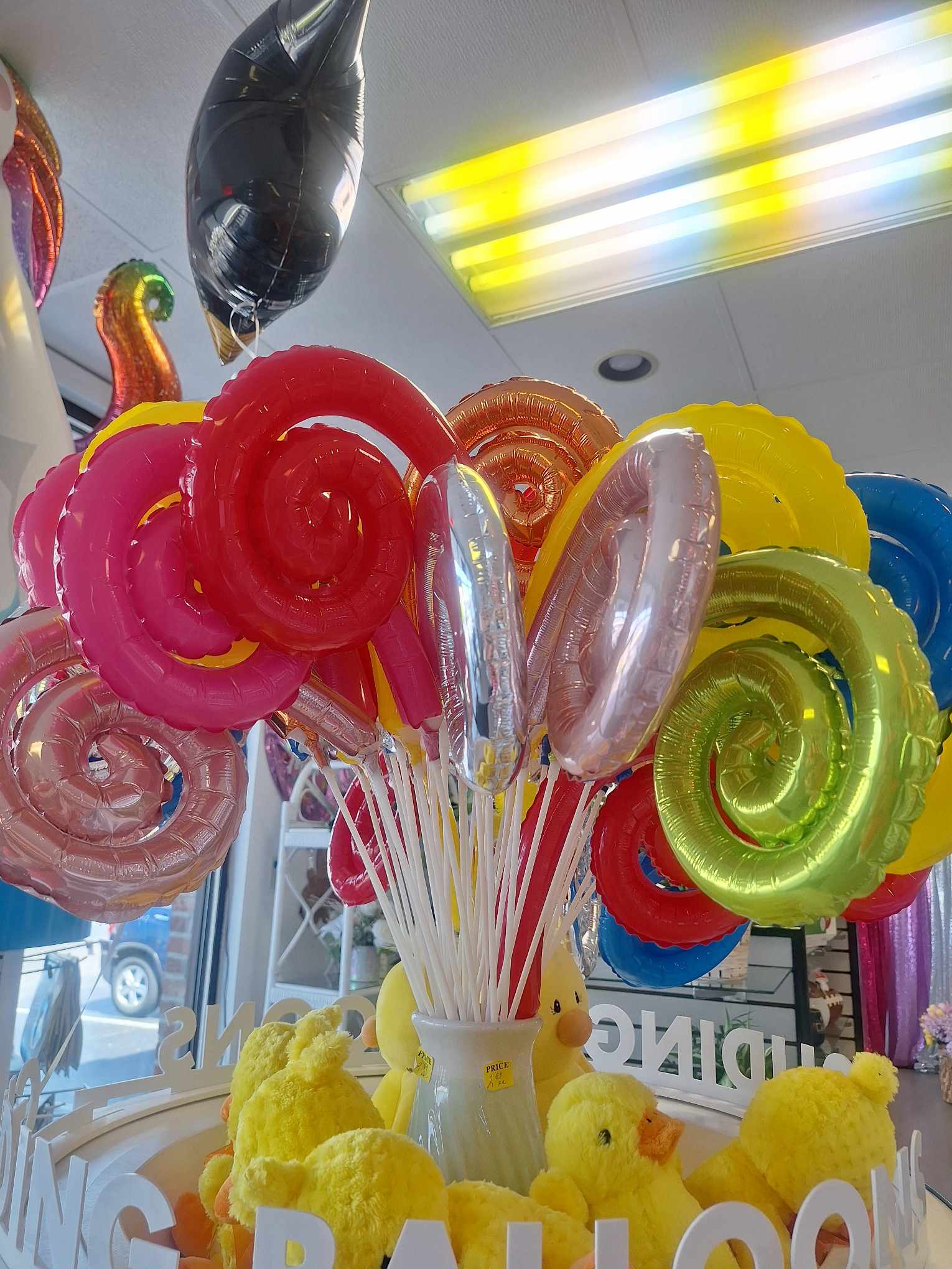 Colorful spiral balloons in a vase with yellow plush chicks