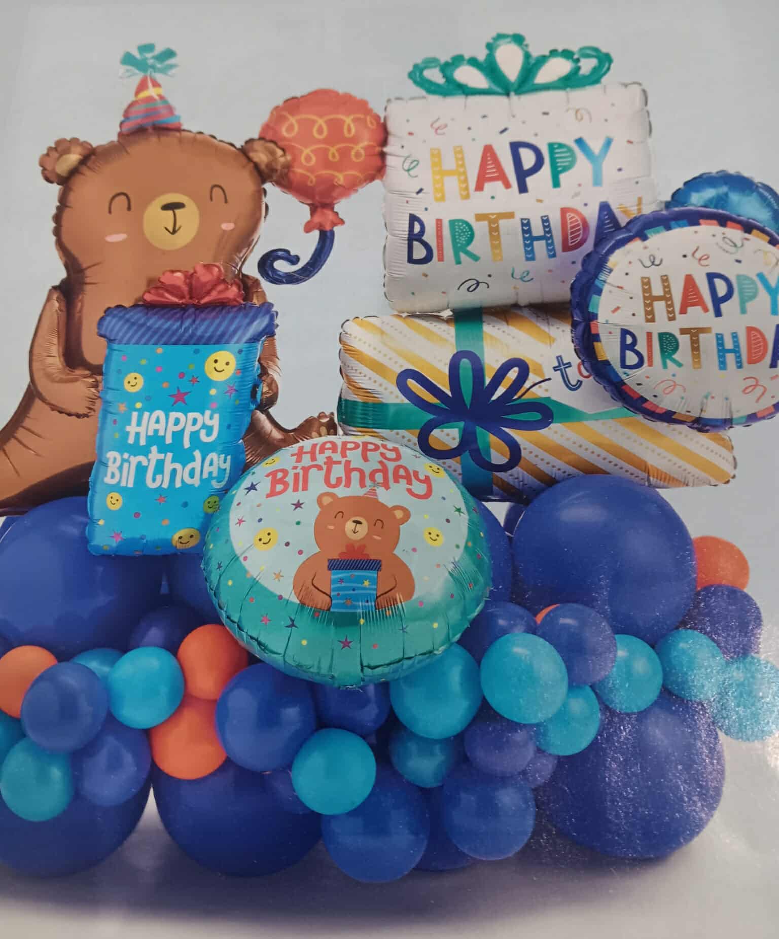 Birthday balloon arrangement with a teddy bear and gift balloons