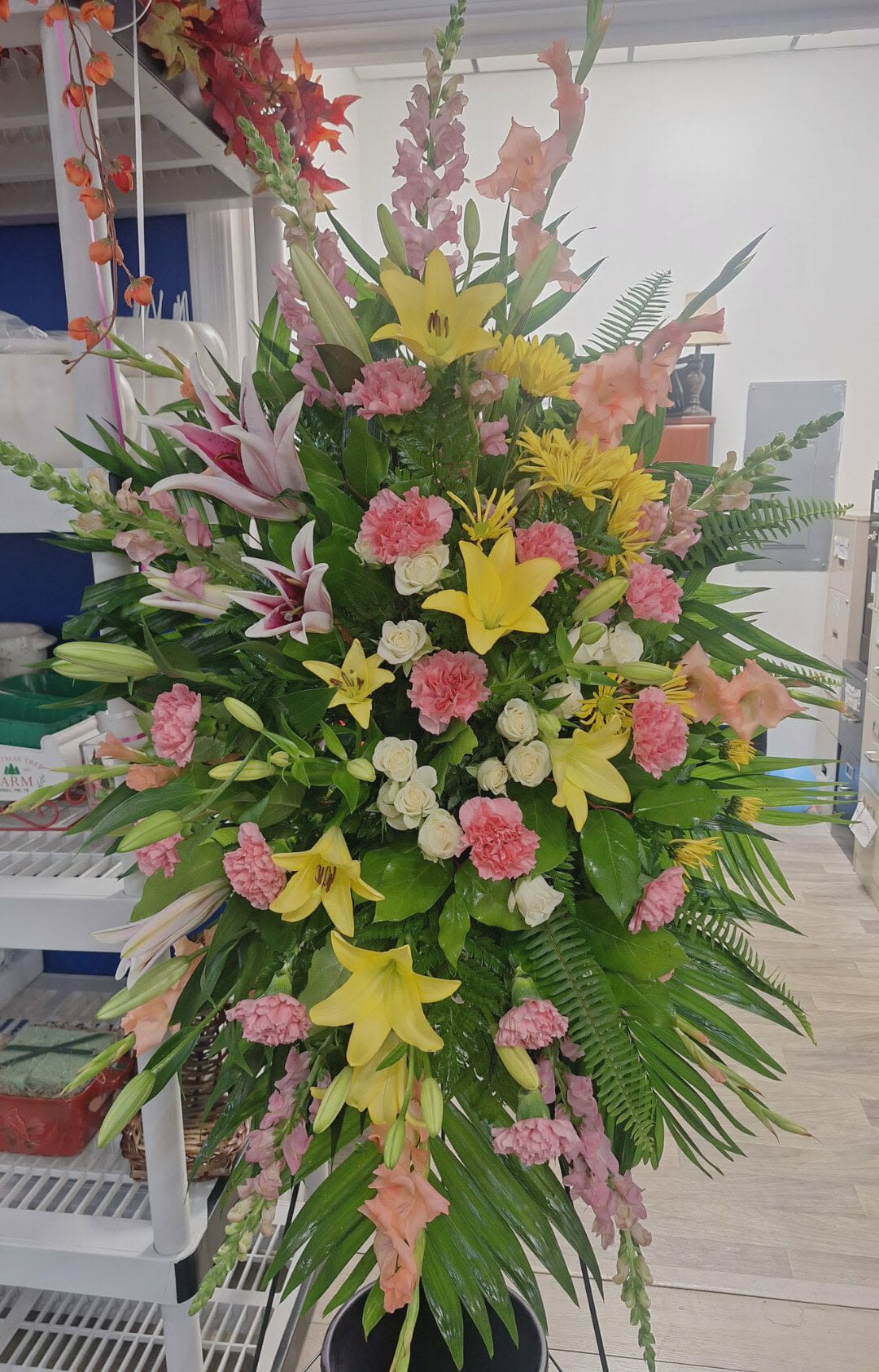 Tall standing floral spray with lilies, carnations, and pink snapdragons