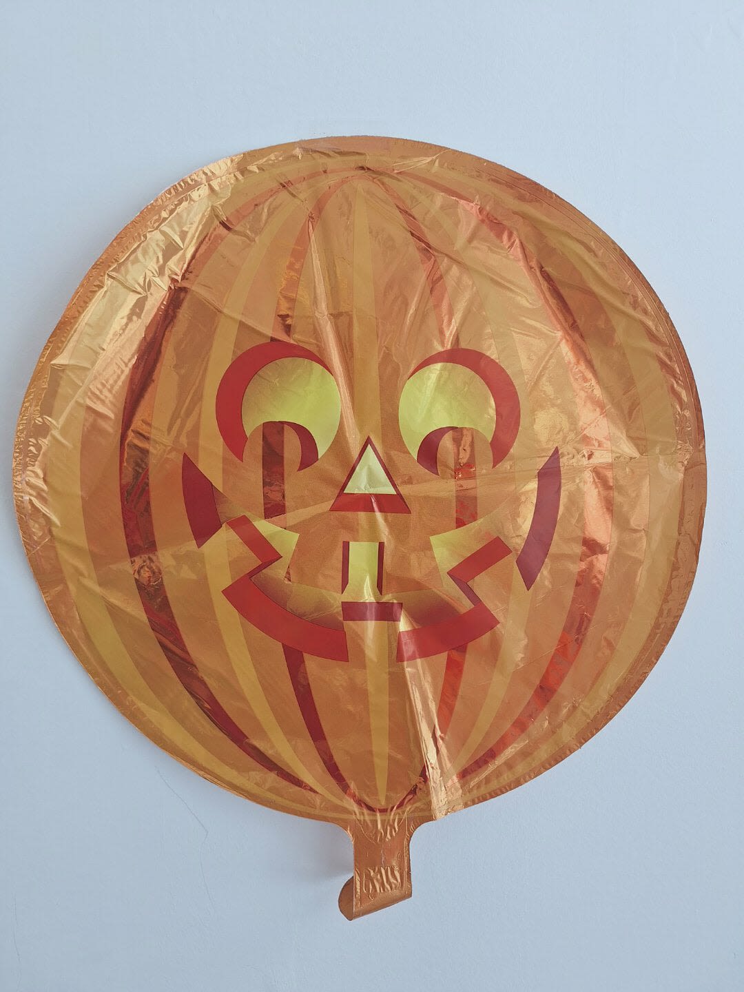 Orange jack-o'-lantern foil balloon against a plain background