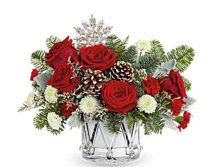 Red roses and white flowers in a clear glass vase with pinecones