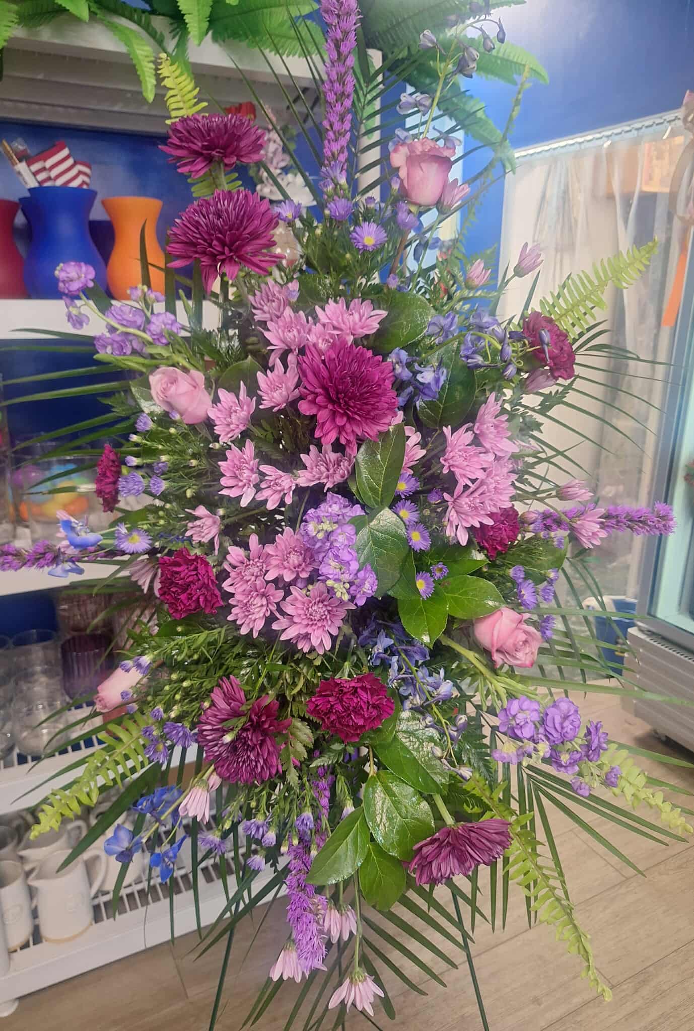 Tall bouquet of pink and purple flowers with palm fronds