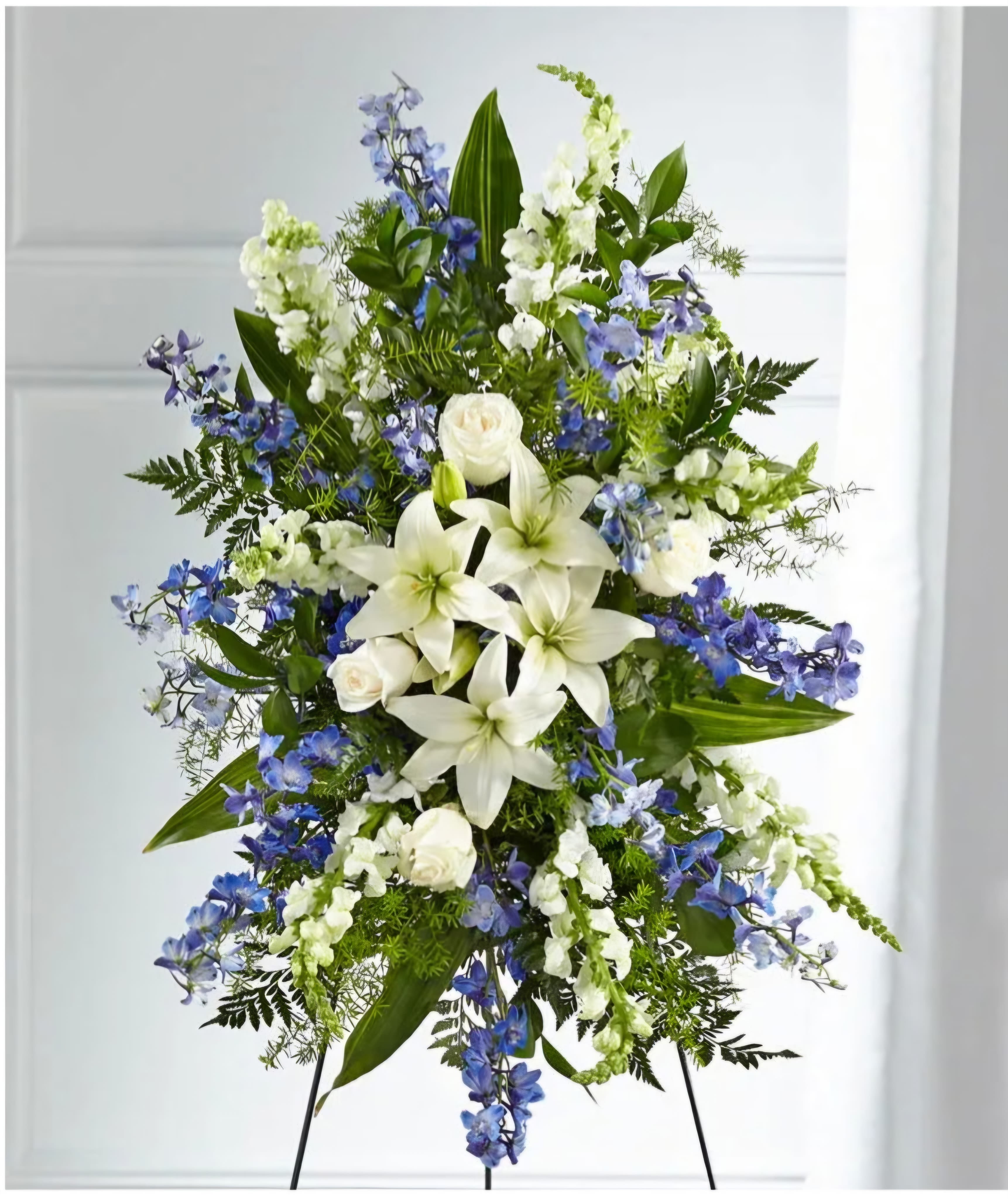 Standing floral spray with white lilies, white roses, and blue flowers