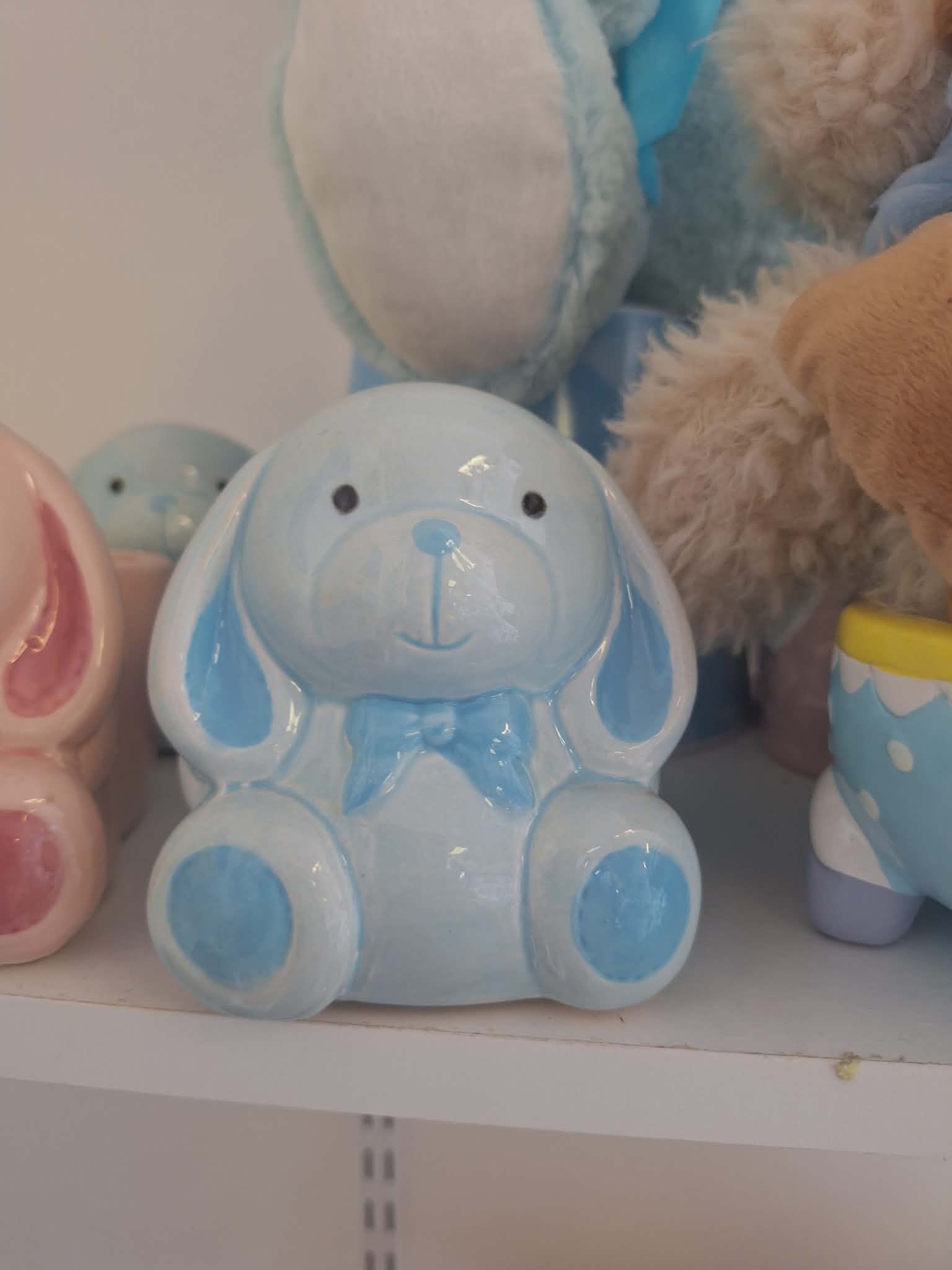 Blue ceramic bunny figurine with a bow sits on a shelf