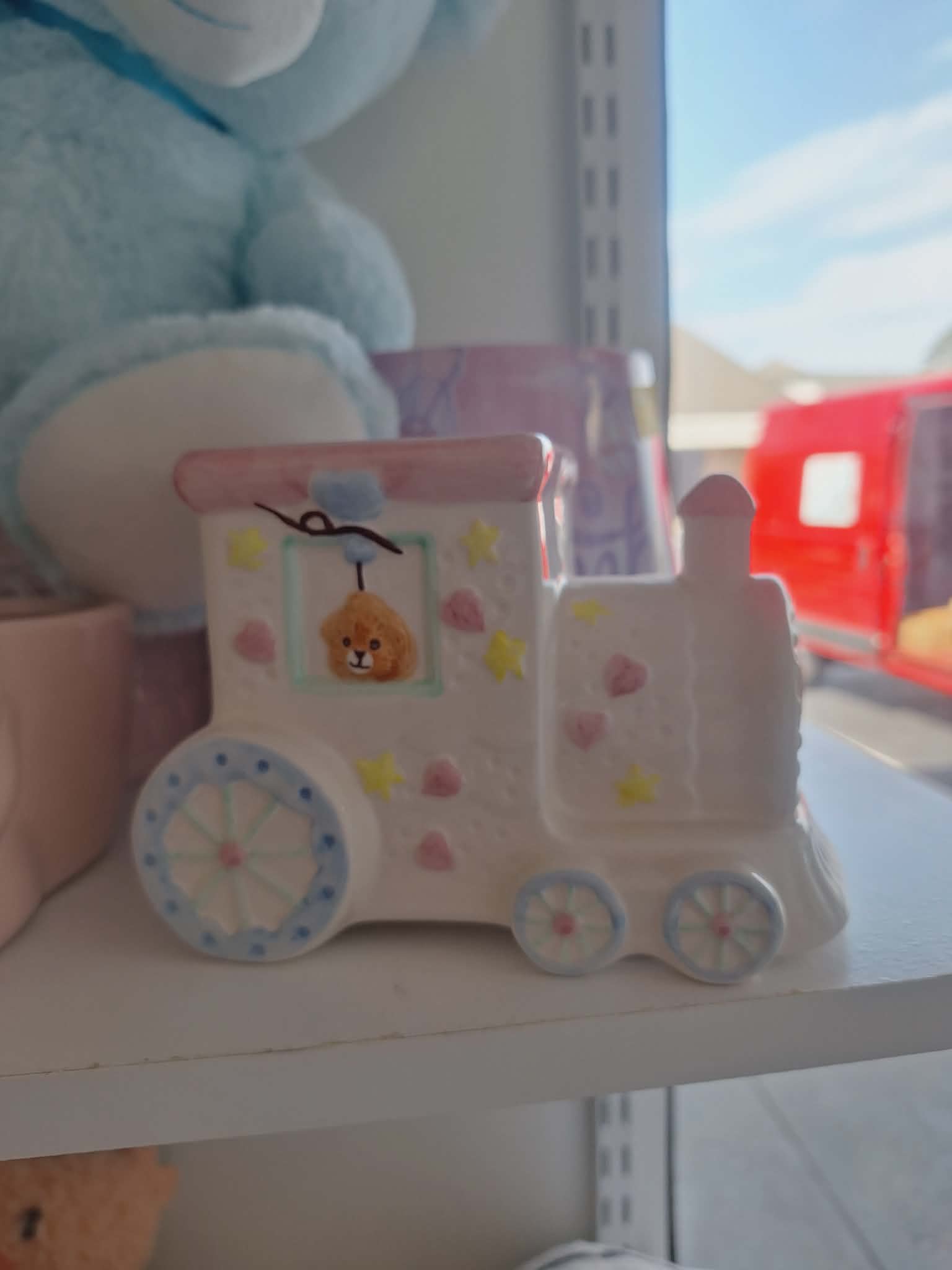 A small painted toy truck with a bear face sits on a shelf.