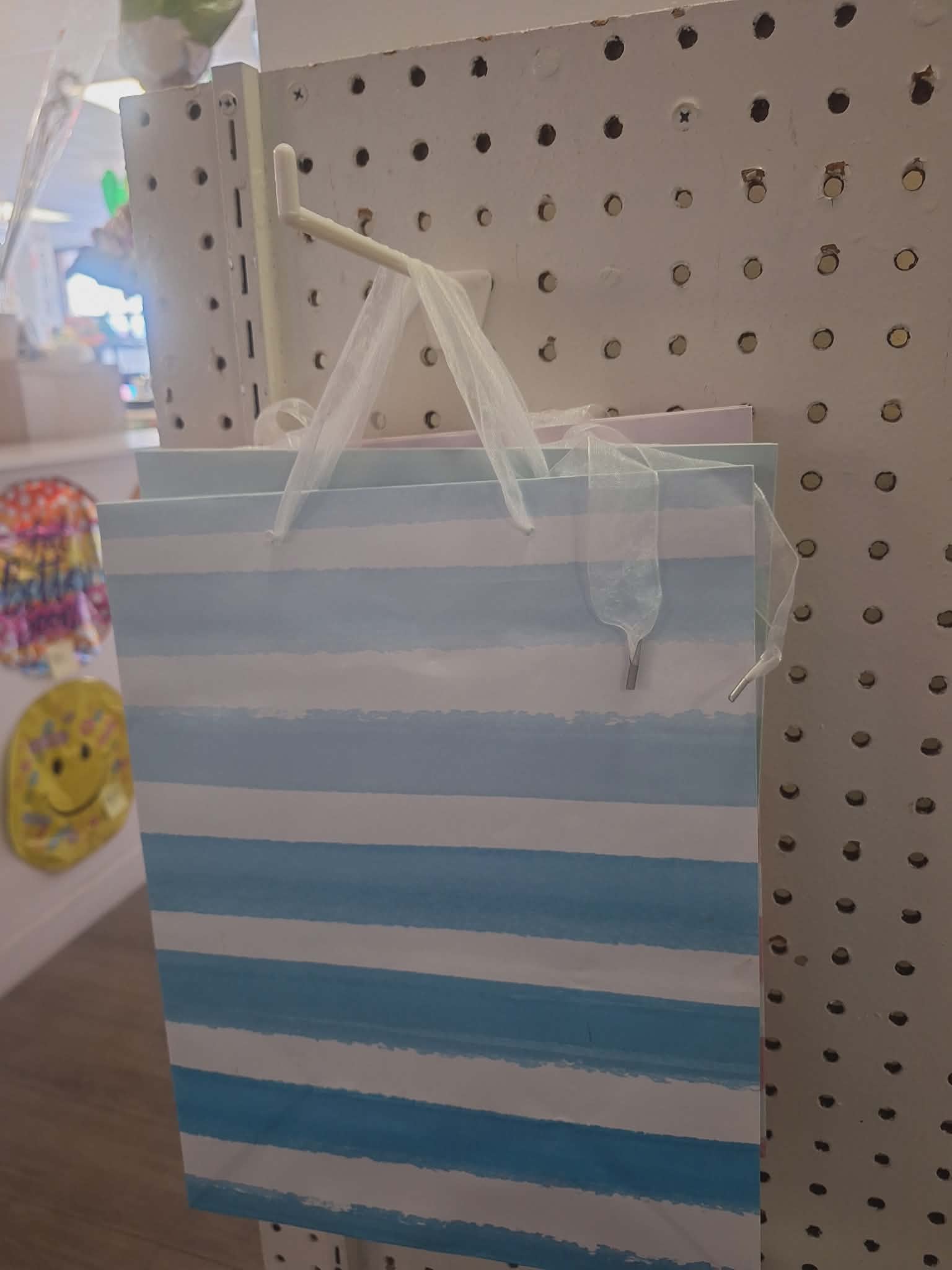 Striped blue-and-white gift bag hanging on a pegboard display
