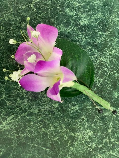 Pink and white calla lily corsage on a green marbled background
