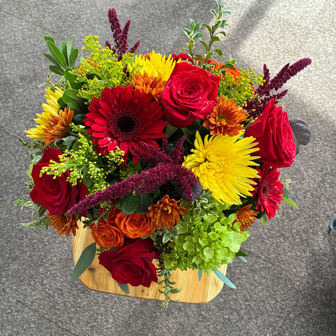 Mixed bouquet with red roses, gerbera daisies, and yellow chrysanthemums in a wooden box