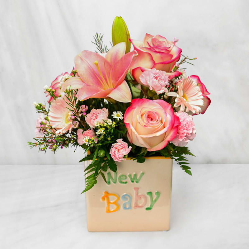 Pink and cream floral arrangement in a "New Baby" container