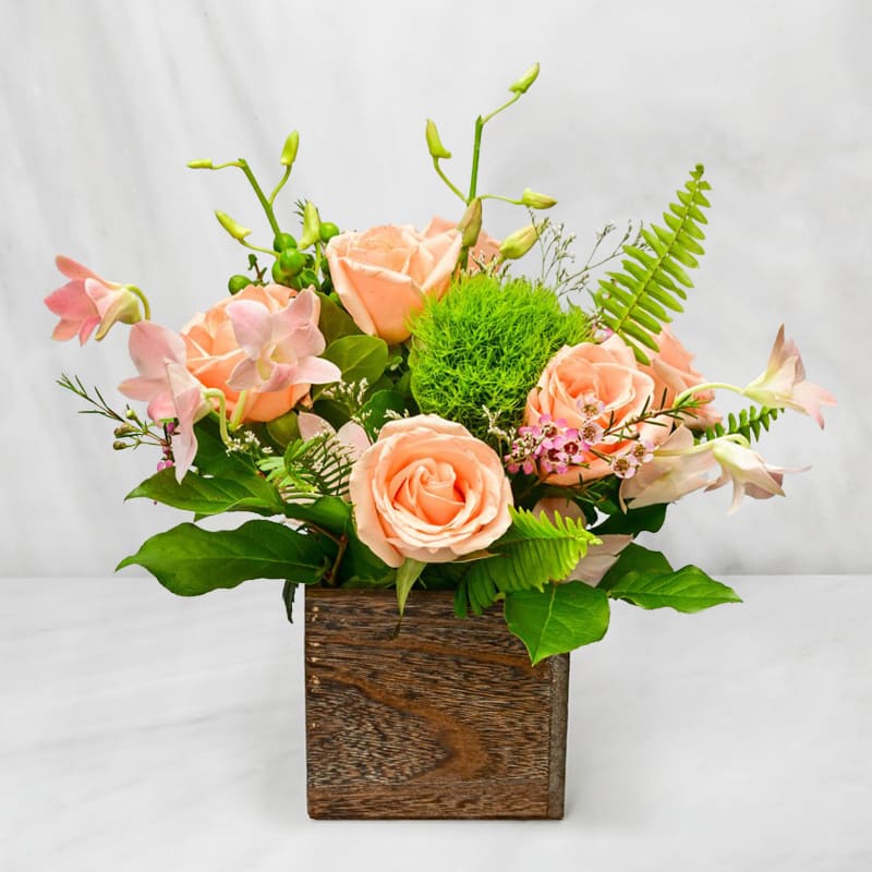 Peach roses and pink orchids in a wooden box arrangement